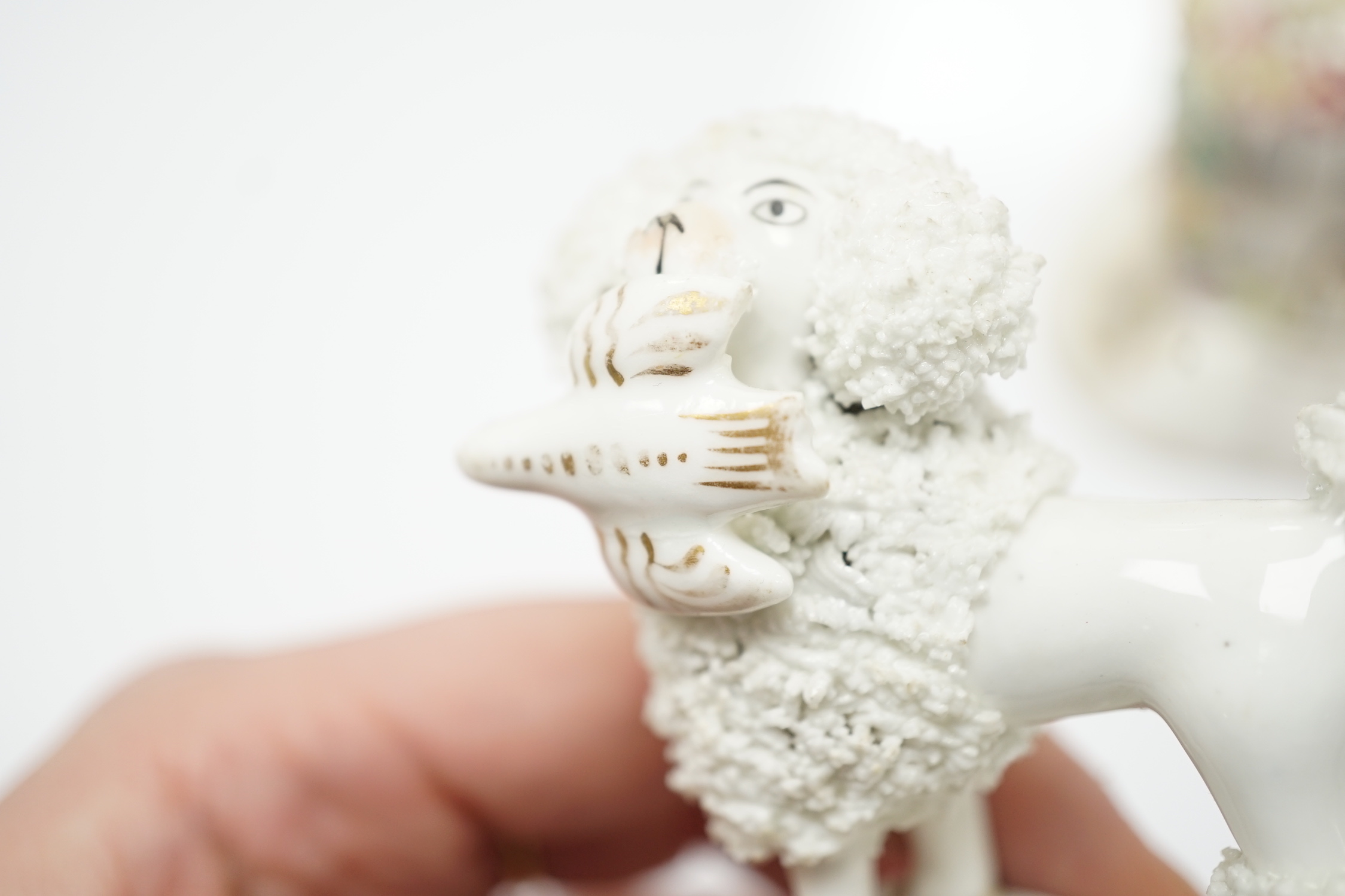 Three Staffordshire porcelain dog figures, c.1830-50, comprising a boy clinging to the back of a spaniel, a model of a poodle with a bird in its mouth and a model of a cottage with a small dog in the doorway, tallest 9cm